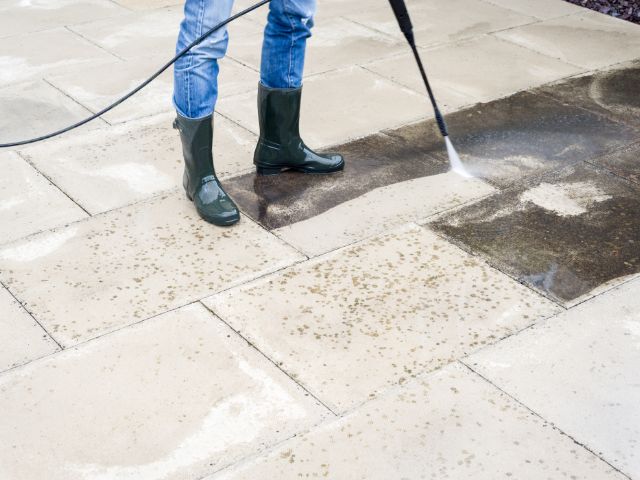 Person pressure cleaning patio
