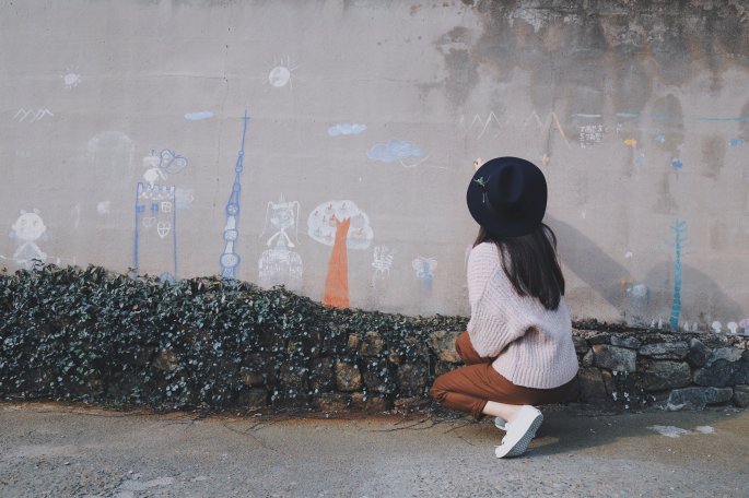 A Little Girl Drawing On A Wall With Chalk